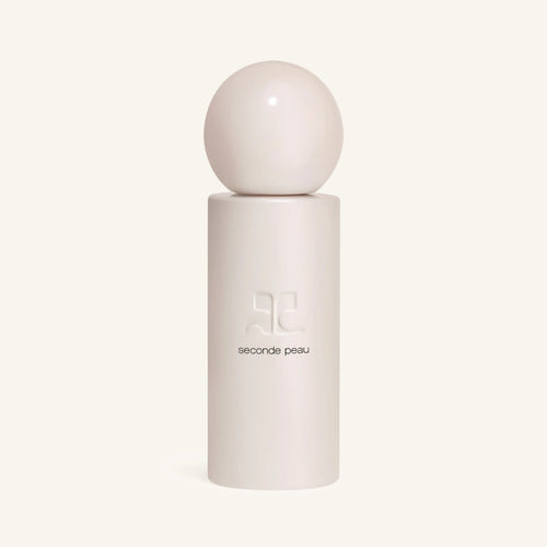 Courrèges Seconde Peau perfume bottle with a white spherical cap atop a tall white cylinder against a pale backdrop