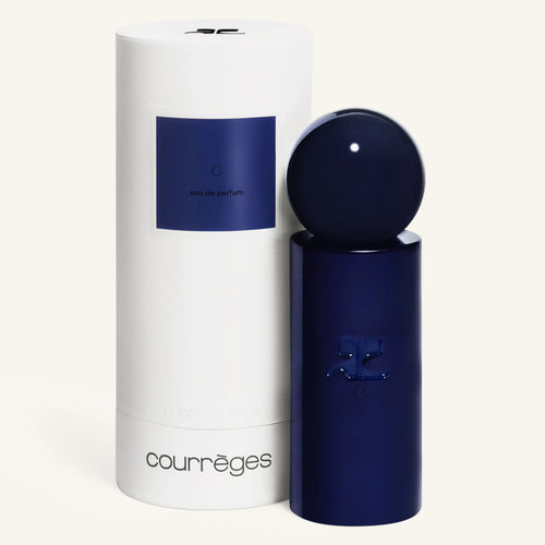 White cylindrical Courrèges packaging with a blue label beside the matching navy bottle