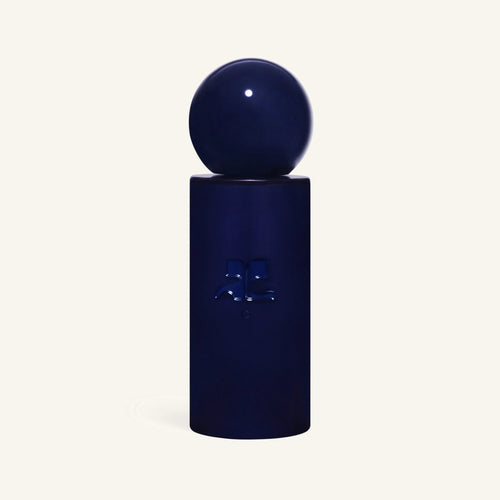 Courrèges C perfume bottle with a round navy cap atop a tall rectangular blue bottle against a pale background