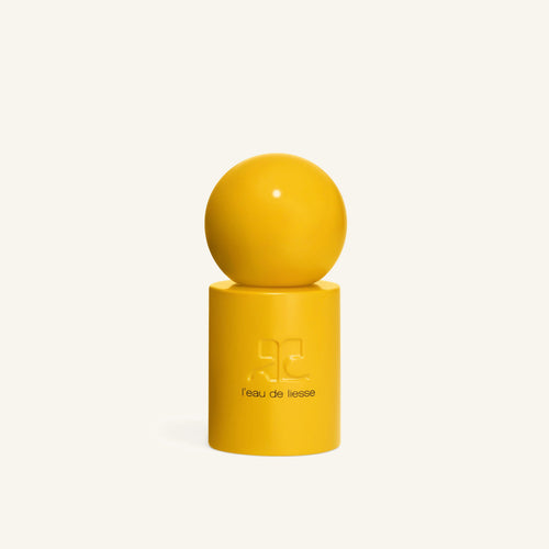 Yellow sphere resting on a tall yellow bottle against a pale background in a minimal Courrèges L eau de liesse display