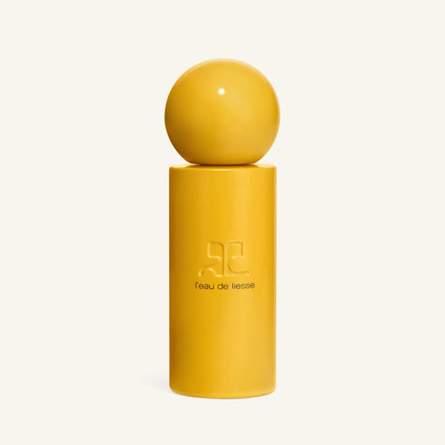 Close-up of a yellow spherical cap atop a matching yellow bottle for L eau de liesse by Courrèges