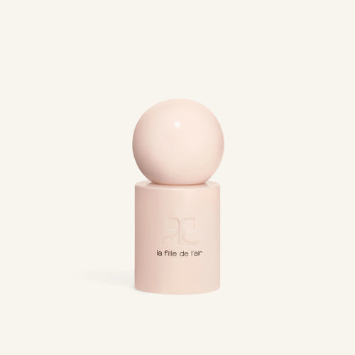 Close up of pale pink cylindrical bottle with embossed logo and rounded top against a cream background