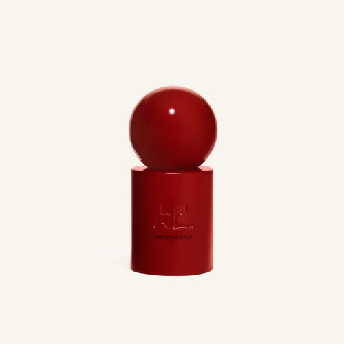 Red spherical cap resting on the red cylindrical bottle of Courrèges L empreinte
