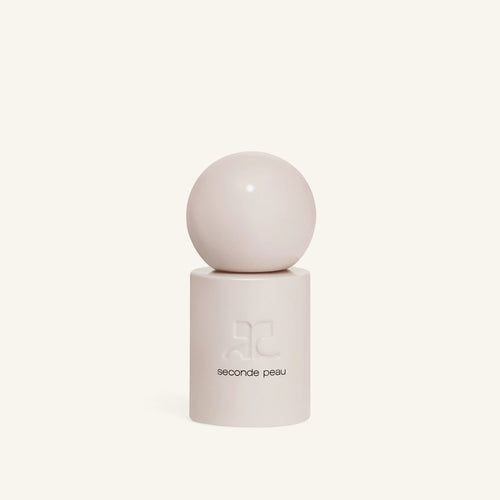 Courrèges Seconde Peau bottle shown from a lower angle, cylindrical body with subtle branding on a pale background